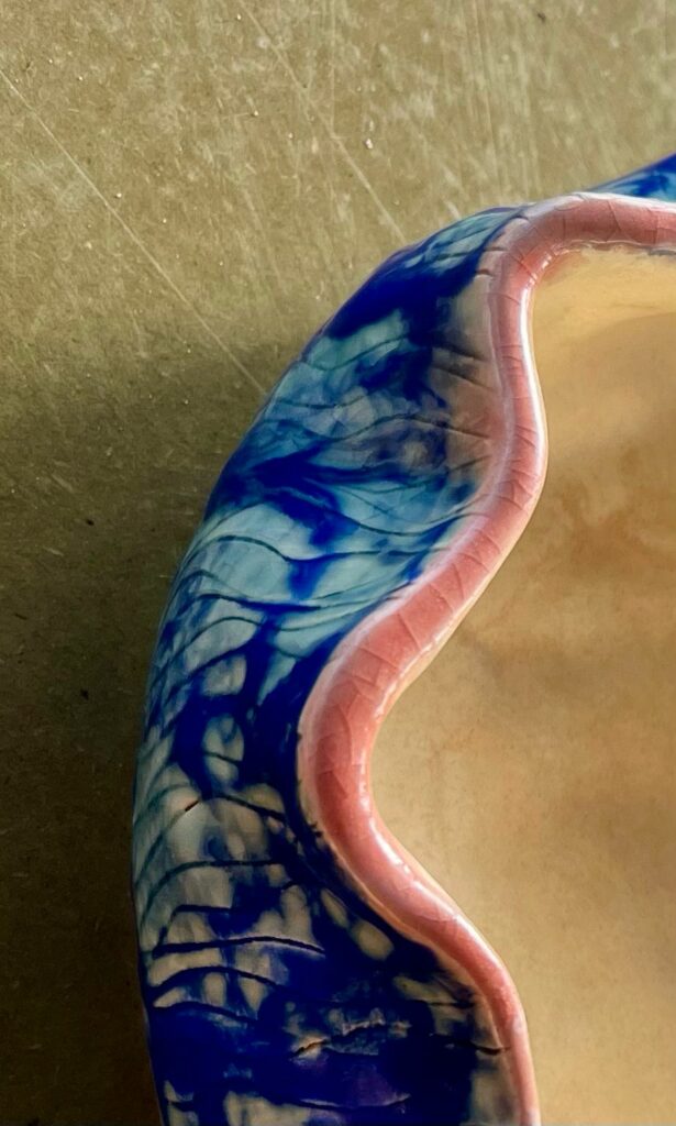 Bol en céramique artisanal aux motifs bleus et bord rose.